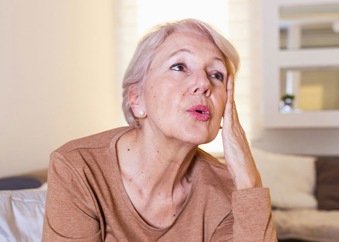 Elderly woman battling cancer looking concerned while sitting indoors, depicting struggle and emotional distress. Elderly woman battling cancer looking concerned while sitting indoors, depicting struggle and emotional distress.