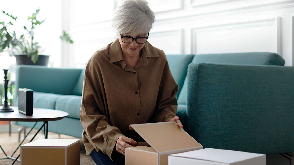 Older woman opening packages at home, illustrating a nosy MIL often opening othersu2019 packages and a surprising gift from DIL.
