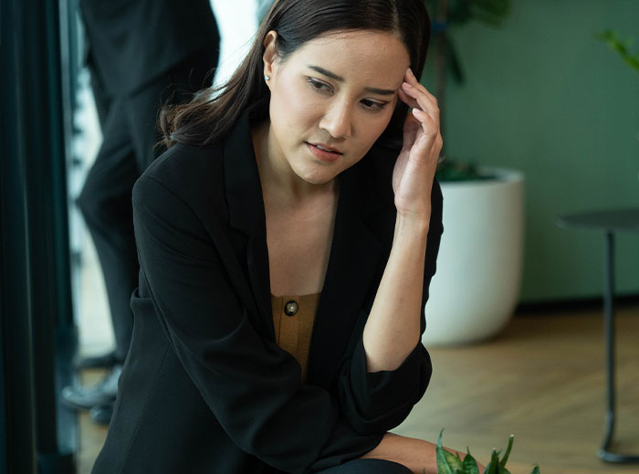 Worried woman sitting indoors, reflecting on family drama involving entitled grandma and grandson’s ashes dispute.