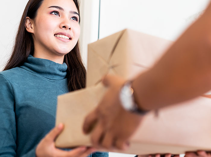 Young woman receiving a package indoors, illustrating family drama involving entitled grandma and grandson’s ashes conflict.