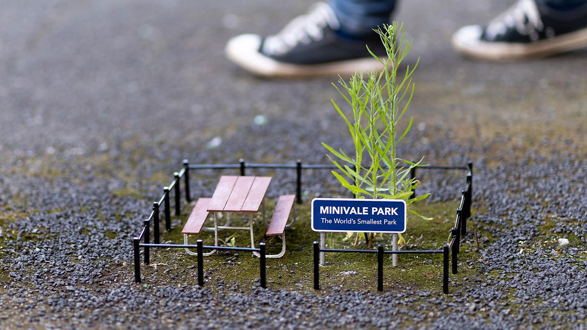 Tiny street scene of Minivale Park with a miniature bench and fence on the sidewalk, part of funny tiny street scenes.