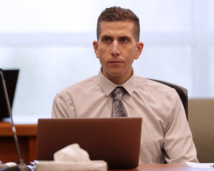 Man in a dress shirt and patterned tie sitting at a desk with a laptop, related to Bryan Kohberger's victim massacre case. Man in a dress shirt and patterned tie sitting at a desk with a laptop, related to Bryan Kohberger's victim massacre case.