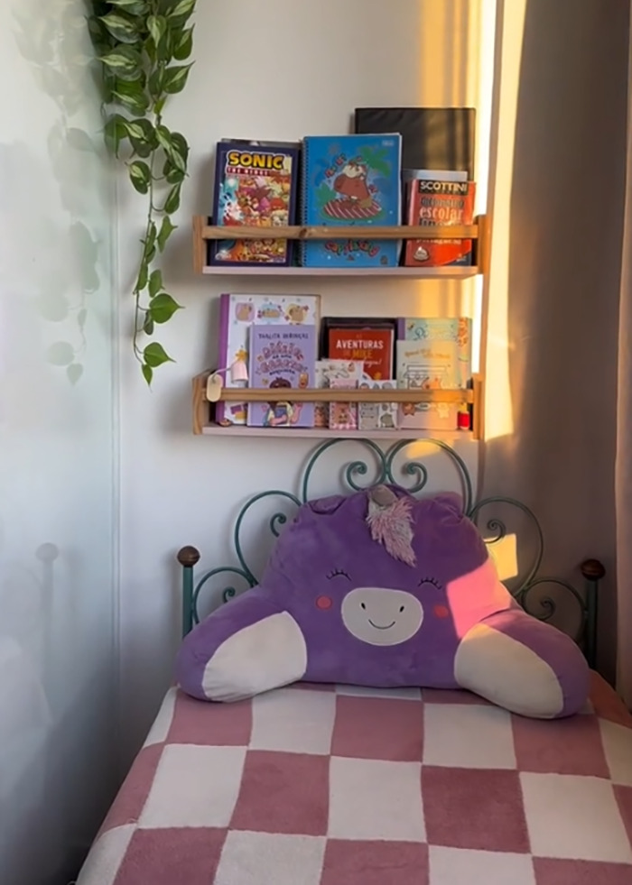 Child's bedroom with stuffed unicorn pillow on bed and shelves holding colorful books in sunlight. Child's bedroom with stuffed unicorn pillow on bed and shelves holding colorful books in sunlight.