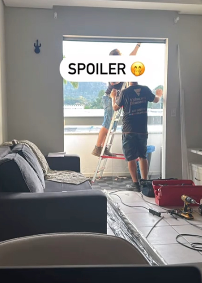 Two people working on balcony renovation in a living room, illustrating momfluencer using room as office with child on balcony. Two people working on balcony renovation in a living room, illustrating momfluencer using room as office with child on balcony.