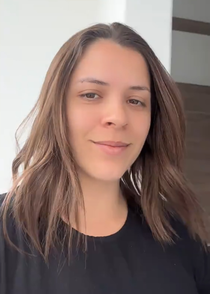 Young woman with shoulder-length brown hair, wearing a black shirt, indoors related to momfluencer and autistic daughter story. Young woman with shoulder-length brown hair, wearing a black shirt, indoors related to momfluencer and autistic daughter story.