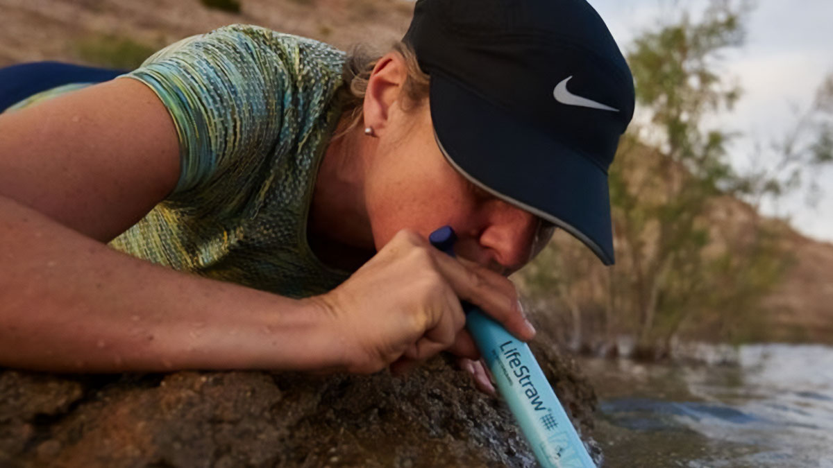 Person using a LifeStraw water filter on a lake shore, highlighting one of the most-wished-for Amazon finds.