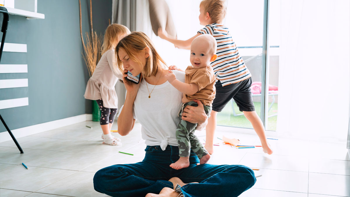 Mother multitasking with children playing around in a messy room, showing family living in filth as a lesson.