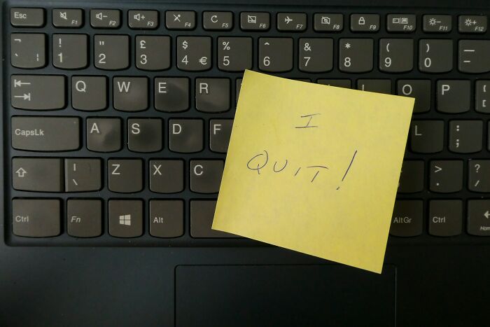 Yellow sticky note with I quit message placed on a black laptop keyboard symbolizing revenge on bosses.
