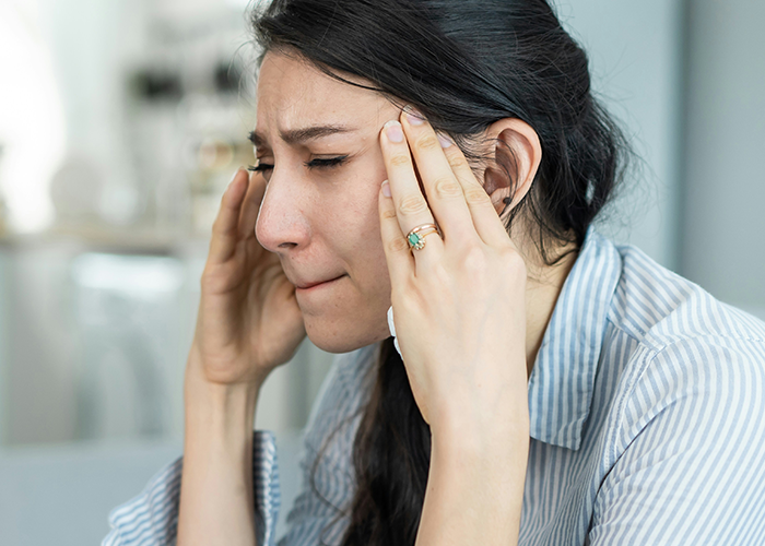 Young woman in striped shirt holding her head, upset about her friend getting fired and consequences that followed. Young woman in striped shirt holding her head, upset about her friend getting fired and consequences that followed.