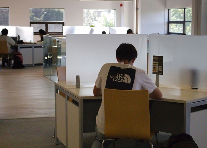 Person seated alone in office cubicle, illustrating workplace tension related to friend getting fired scenario.