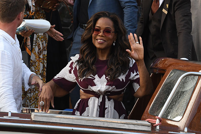 Oprah smiling and waving while surrounded by people on a boat, controversial private road and tsunami access topic. Oprah smiling and waving while surrounded by people on a boat, controversial private road and tsunami access topic.