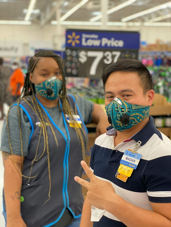 Two Walmart employees wearing patterned face masks inside store showing peace sign, related to arrogant people keyword.