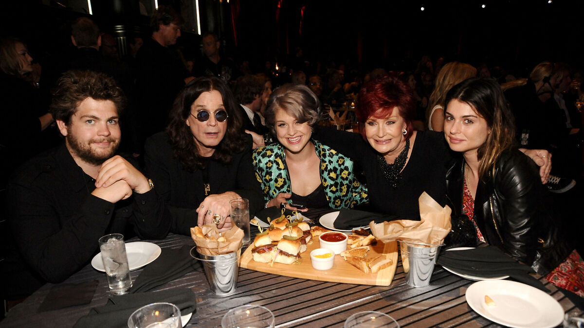 Ozzy Osbourne and family sitting at a table with food, highlighting family rifts after kids were snubbed in tribute.