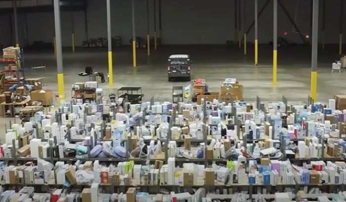 Large warehouse filled with hundreds of Amazon packages mistakenly delivered and stacked in rows.