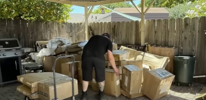 Man sorting hundreds of Amazon packages mistakenly delivered to woman's home under a covered outdoor patio area. Man sorting hundreds of Amazon packages mistakenly delivered to woman's home under a covered outdoor patio area.