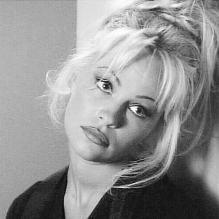 Black and white close-up of Pamela Anderson looking thoughtful with tousled hair and soft lighting in a portrait style image. Black and white close-up of Pamela Anderson looking thoughtful with tousled hair and soft lighting in a portrait style image.