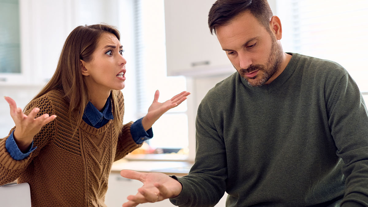 Woman angrily confronting partner while he looks away, showing tension in relationship about caring for children with other men.