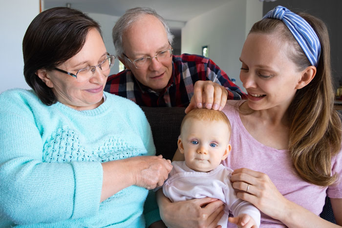 Mom with baby and in-laws helping care, showing overprotective family dynamics and mixed emotions. Mom with baby and in-laws helping care, showing overprotective family dynamics and mixed emotions.