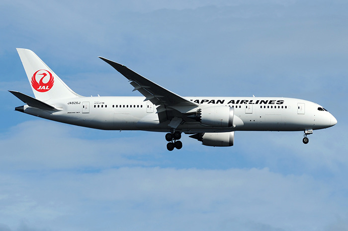 Japan Airlines airplane in flight with landing gear extended under a clear blue sky, related to passengers writing farewell messages. Japan Airlines airplane in flight with landing gear extended under a clear blue sky, related to passengers writing farewell messages.