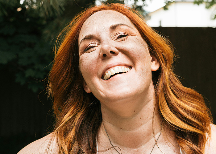 Red-haired woman smiling outdoors, conveying confidence and attitude related to savage insults shared by people.