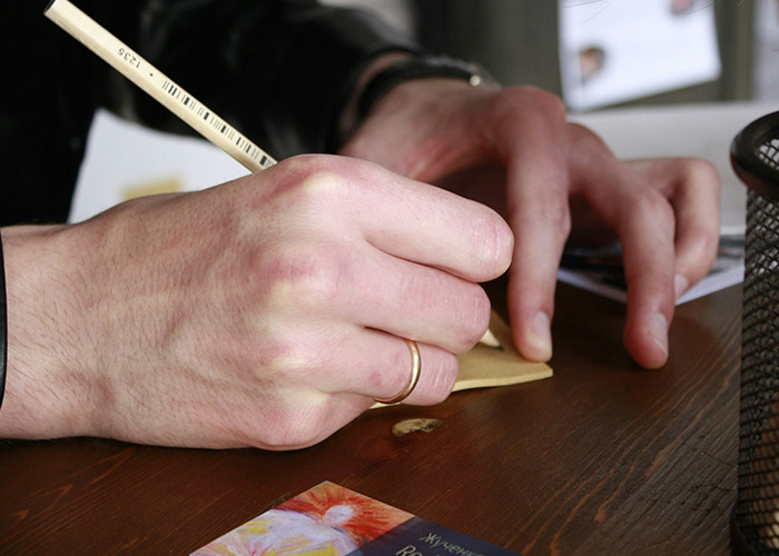Close-up of a person writing with a pencil on paper, illustrating the theme of savage insults shared by people.