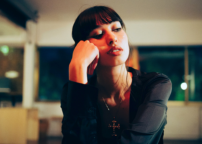 Young woman looking thoughtful and bored indoors, expressing a mood fitting savage insults and witty comebacks.