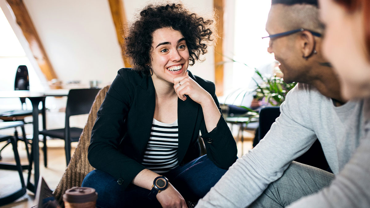 Young people smiling and talking indoors, sharing savage insults in a casual social setting.