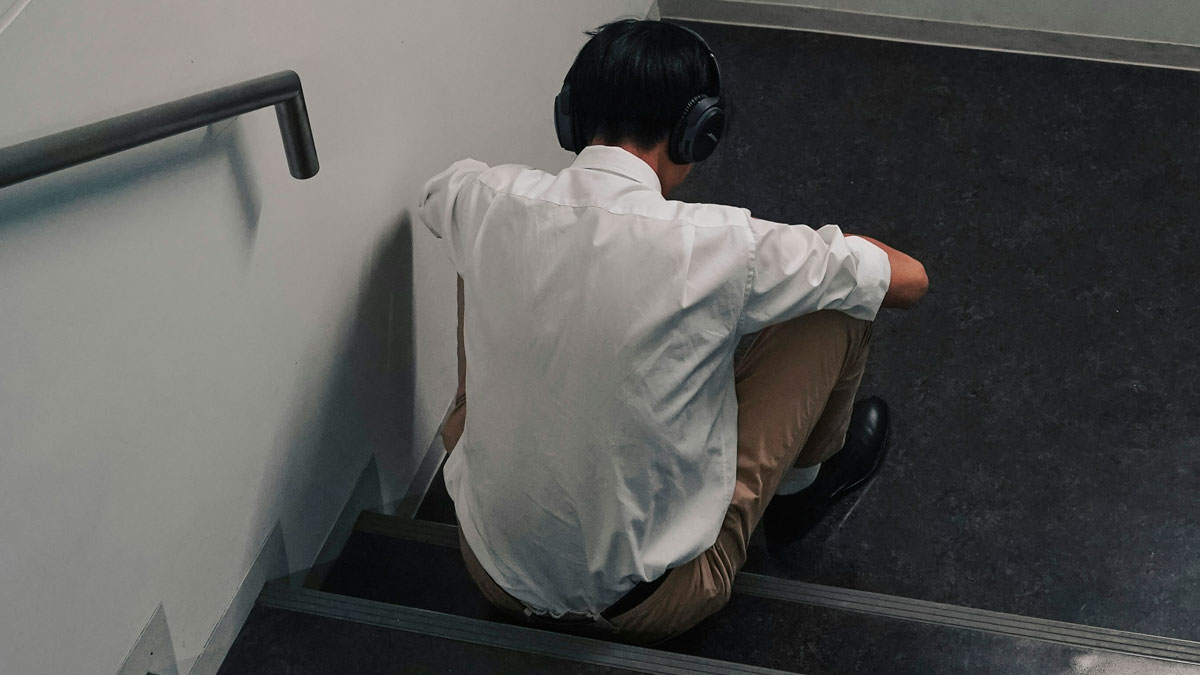 Young man wearing headphones sitting alone on stairs, illustrating red flag in relationships needing a parent not partner