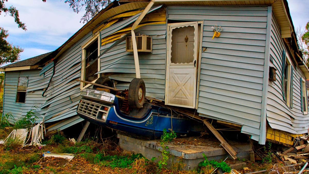 Damaged house with a blue truck embedded under the porch, illustrating perception challenges in psychology experiments.