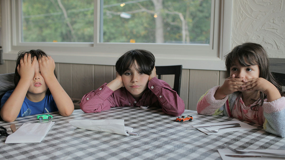 Three children at table with checkered cloth, showing expressions of frustration and silence, reflecting unhappy marriages theme.