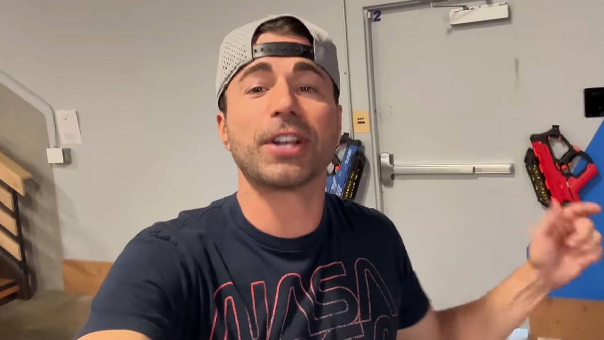 Man wearing a backward cap and NASA shirt, speaking energetically in a room, people share unsubscribed YouTubers concept.