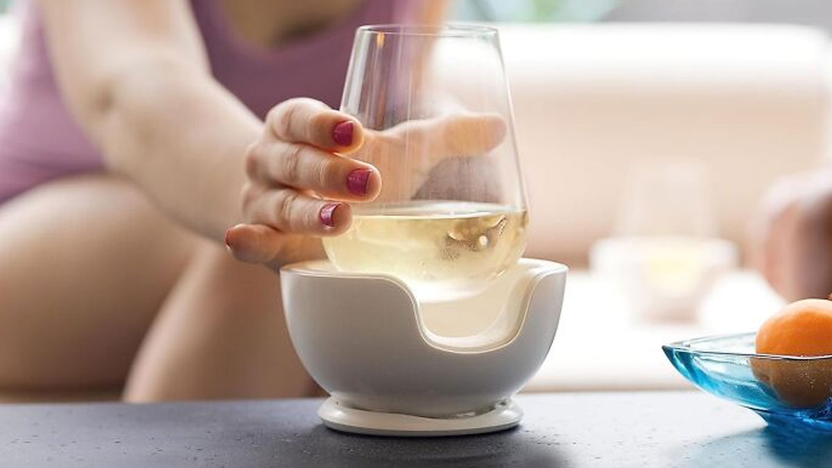 Hand holding a glass of white wine with a coaster, ideal for perfect gifts that arrive by tomorrow.
