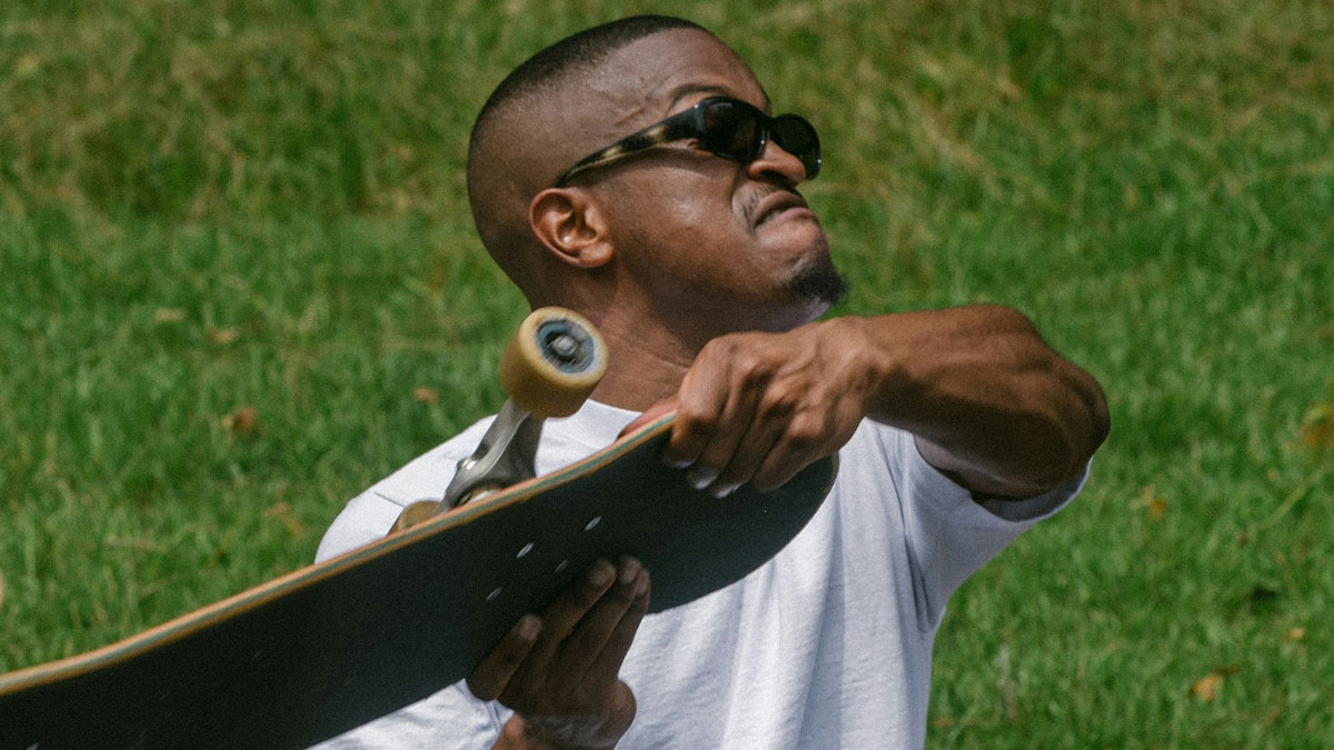 Man wearing sunglasses holding a skateboard with a determined expression, highlighting hard-to-believe stories about themselves