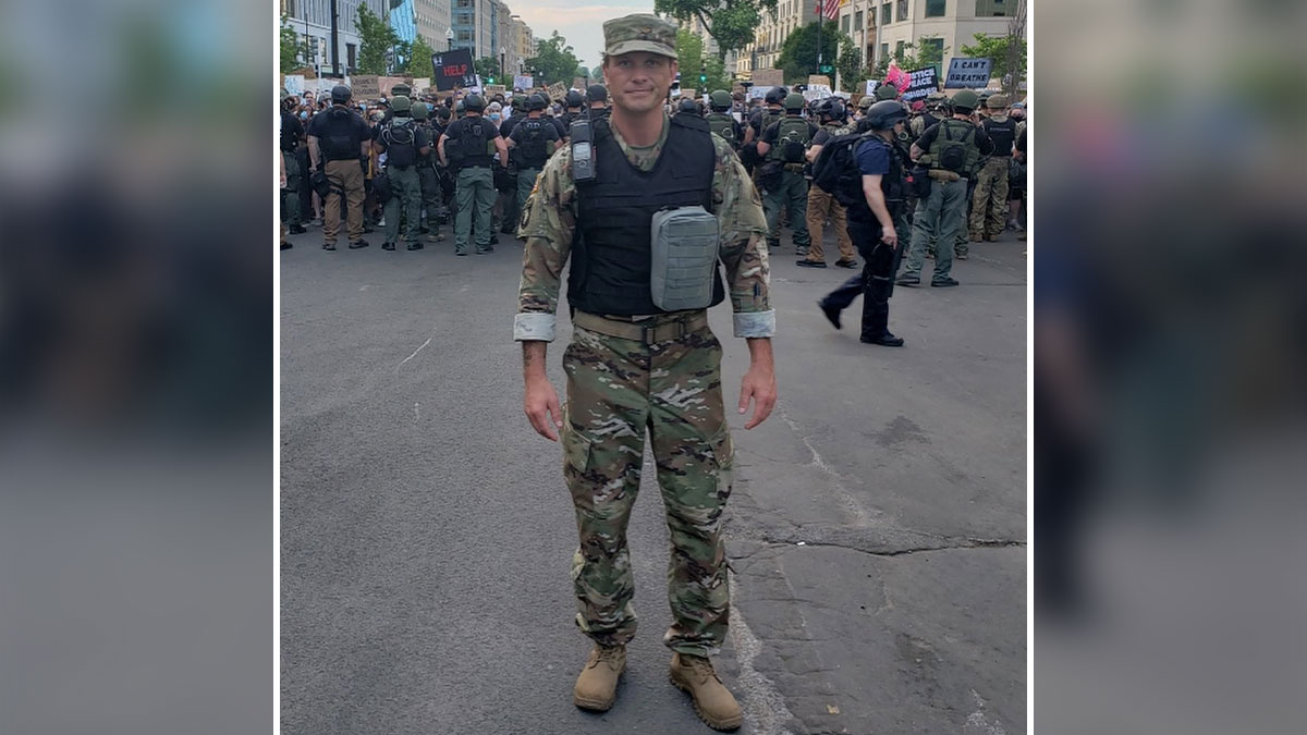 Pete Hegseth in military uniform standing on a city street with a crowd of law enforcement officers behind him.
