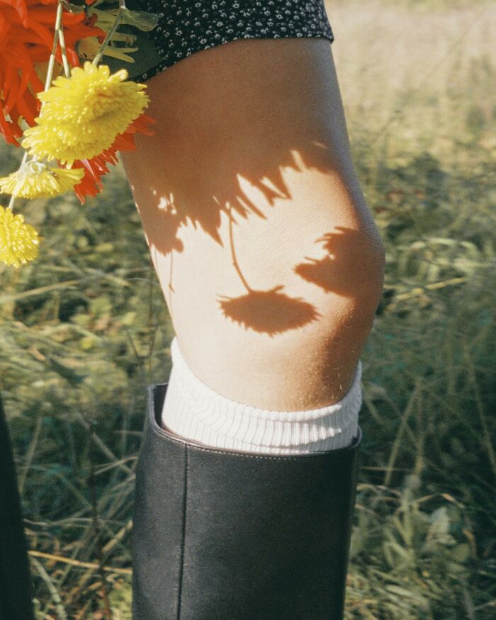 Person holding yellow flowers with shadows cast on their leg outdoors, highlighting scientists share use bodies donated science.