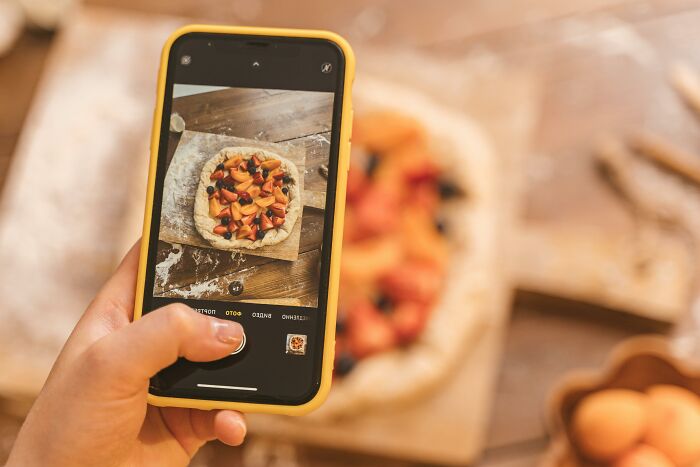Person using a smartphone to photograph food, highlighting the global food waste crisis and its environmental impact.