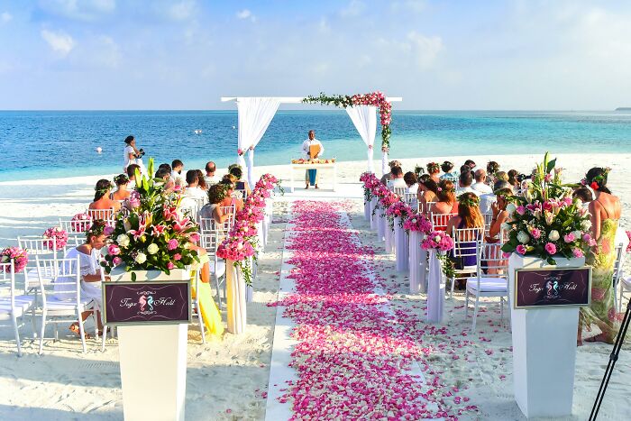 Beach wedding setup with floral decorations and guests seated, highlighting signs couples' days may be numbered.
