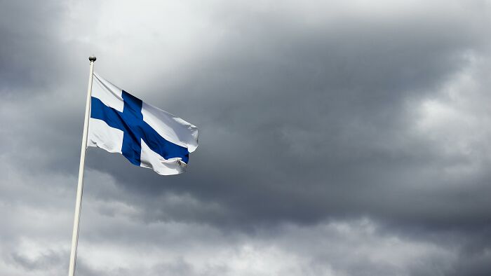 Flag of Finland waving against a dark cloudy sky, representing one of the smartest countries shaping the future.