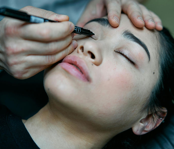 Close-up of a woman receiving cosmetic marking on her face before plastic surgery to achieve a youthful Asian childlike look. Close-up of a woman receiving cosmetic marking on her face before plastic surgery to achieve a youthful Asian childlike look.