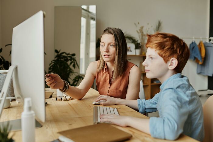 Woman teaching boy at computer, focusing on a task involving kitchen tools and everyday objects to name as many as possible. Woman teaching boy at computer, focusing on a task involving kitchen tools and everyday objects to name as many as possible.
