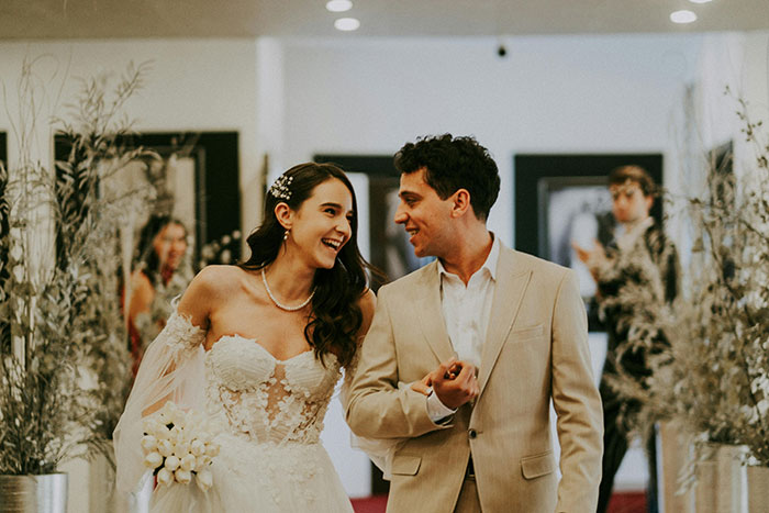 Bride and groom smiling at wedding ceremony, with guests in background, capturing best man’s speech moment.