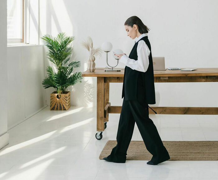 Woman in black and white outfit walking indoors near a wooden desk, illustrating people who took revenge on their bosses.
