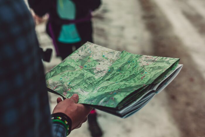 Person holding and examining a folded world map outdoors, focusing on identifying 30 countries from Brazil to Greece locations. Person holding and examining a folded world map outdoors, focusing on identifying 30 countries from Brazil to Greece locations.