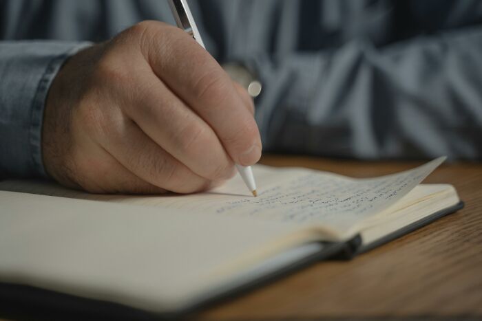 Hand of a teacher writing notes in a notebook about truly outrageous student names in an educational setting