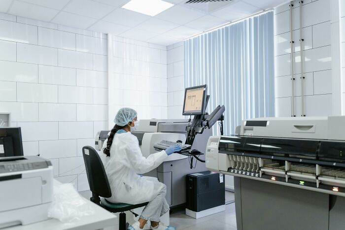 Scientist in lab coat and hairnet using computer and lab equipment in a sterile room for bodies donated science research.