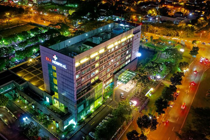 Aerial night view of a hospital building with surrounding roads and trees, illustrating scientists sharing bodies donated for science.