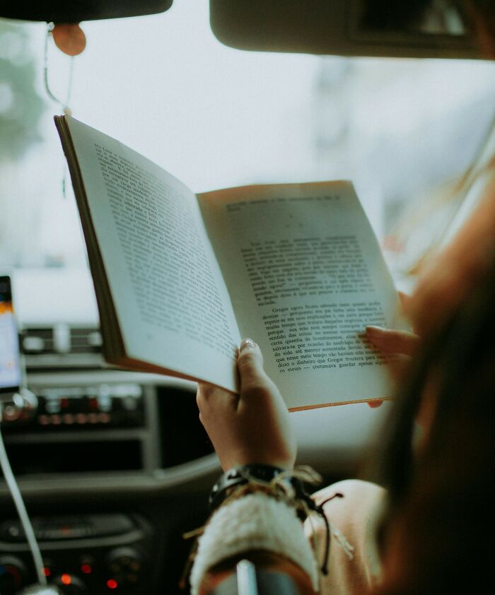 Person reading a book inside a truck cabin, illustrating truckers share craziest things seen on the road.