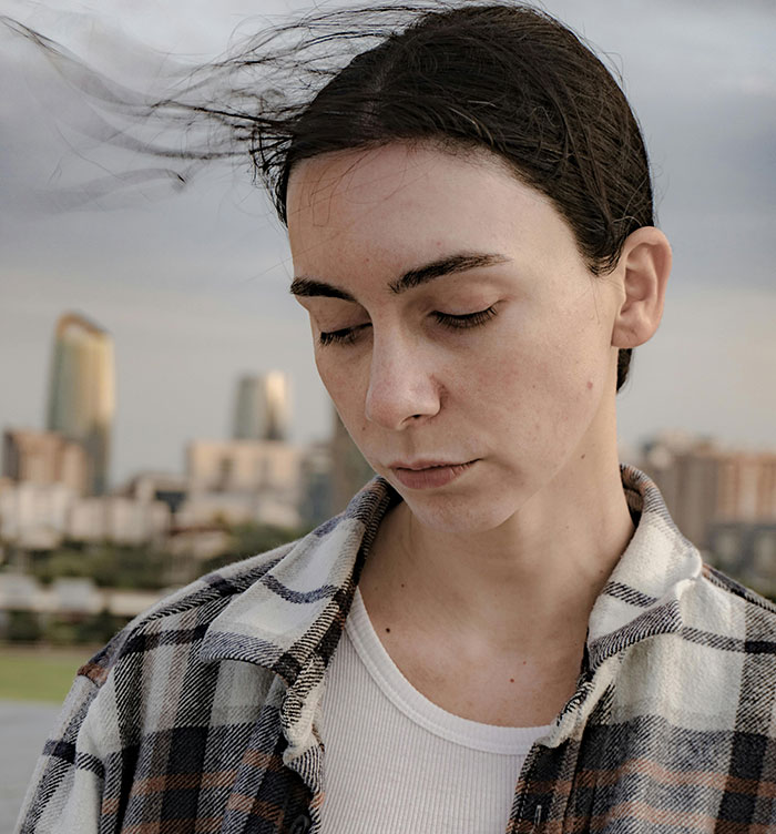 Young woman outdoors looking down thoughtfully, illustrating best friend sabotage in relationship with boyfriend feelings.