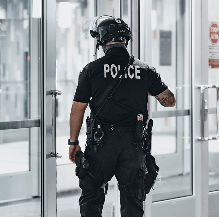 Police officer in tactical gear seen from behind, responding to incident involving man threatening to explode plane mid-flight. Police officer in tactical gear seen from behind, responding to incident involving man threatening to explode plane mid-flight.
