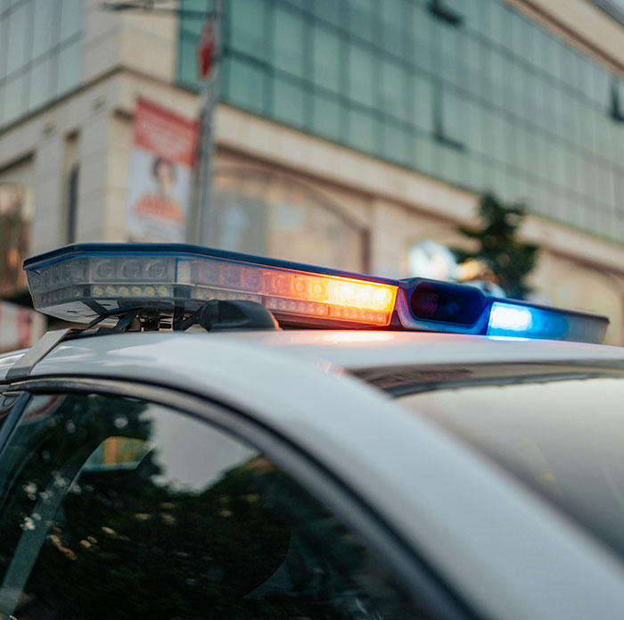 Police car with flashing lights parked near a building, related to man threatening to explode plane mid-flight incident. Police car with flashing lights parked near a building, related to man threatening to explode plane mid-flight incident.
